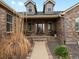 Inviting covered porch with chairs and brick accents, leading to the front door of the home at 5708 Wetland Loop, Frederick, CO 80504