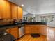 Kitchen featuring wood cabinets, dark countertops, stainless steel dishwasher and floors at 5708 Wetland Loop, Frederick, CO 80504