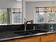 Kitchen sink with a dark granite countertop, wood cabinets, and views from the two windows at 5708 Wetland Loop, Frederick, CO 80504