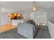 Open living space featuring plush gray carpeting, a ceiling fan, and views of the kitchen and front door at 5708 Wetland Loop, Frederick, CO 80504