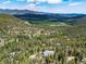 Scenic aerial view of the house nestled among lush trees and a picturesque mountain landscape at 6882 Snowshoe Trl, Evergreen, CO 80439