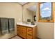 Bathroom with wooden cabinets, single sink, large mirror, and outside view at 6882 Snowshoe Trl, Evergreen, CO 80439