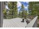 Deck with a table and chair set nestled amongst the pine trees at 6882 Snowshoe Trl, Evergreen, CO 80439