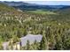 Aerial view revealing a mountain valley filled with green trees and homes nestled within at 6882 Snowshoe Trl, Evergreen, CO 80439