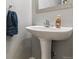 Cozy powder room featuring a pedestal sink, blue hand towel, and neutral paint with a decorative mirror at 23535 E Platte Dr # A, Aurora, CO 80016