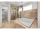 Bathroom boasts a glass shower and tiled jacuzzi tub beneath a bright window at 44000 E 88Th Ave, Bennett, CO 80102
