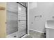 Bright bathroom featuring a tiled shower with glass doors, modern fixtures, and gray textured walls at 44000 E 88Th Ave, Bennett, CO 80102