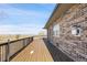 Spacious wood deck with railing, brick exterior, and peaceful rural views at 44000 E 88Th Ave, Bennett, CO 80102