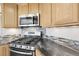 Close-up of the kitchen featuring a gas range, microwave, and stone countertops at 44000 E 88Th Ave, Bennett, CO 80102