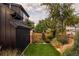 Beautiful backyard featuring green artificial grass, lush landscaping, and a tall wooden privacy fence at 1983 S Logan St, Denver, CO 80210