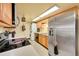 Efficient kitchen features wooden cabinets, sink, dishwasher, stainless appliances, and stacked washer/dryer at 1212 S Uvalda St, Aurora, CO 80012