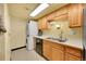 Efficient kitchen features wooden cabinets, sink, dishwasher, and stacked washer/dryer at 1212 S Uvalda St, Aurora, CO 80012