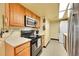 Efficient kitchen features wooden cabinets, tile floors, and stainless appliances at 1212 S Uvalda St, Aurora, CO 80012