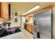 Efficient kitchen features wooden cabinets, tile floors, stainless appliances, and stacked washer/dryer at 1212 S Uvalda St, Aurora, CO 80012