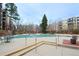 Outdoor pool area with seating and tables, surrounded by trees and landscaping at 3450 S Poplar St # 307, Denver, CO 80224