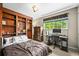 Comfortable bedroom featuring built-in bookshelves, natural light from a window, and dedicated desk area at 12625 W 66Th Cir, Arvada, CO 80004