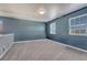 Cozy bedroom featuring neutral carpet, blue walls, white trim, and two windows providing natural light at 23957 E Rocky Top Ave, Aurora, CO 80016