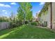 Well-maintained backyard featuring lush green lawn, garden beds, mature trees, and a charming brick retaining wall at 8944 W 66Th Pl, Arvada, CO 80004