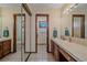 Bright bathroom with dual sinks, vanity, tile floor, and a separate toilet room at 8944 W 66Th Pl, Arvada, CO 80004