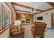 Cozy living room featuring a brick fireplace, wood beams, and comfortable seating at 8944 W 66Th Pl, Arvada, CO 80004