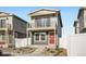 Charming two-story home with a balcony and a red front door is framed by a white picket fence at 5035 N Walden Way, Denver, CO 80249