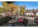 Balcony view of mature trees and parking, furnished with seating and a small table at 7755 E Quincy # 201, Denver, CO 80237