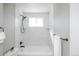 Clean, bright white tiled bathtub/shower combination with black fixtures and a large window at 4933 W 61St Ave, Arvada, CO 80003