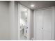 Hallway featuring a view into an updated bathroom and a closet with louvered doors at 4933 W 61St Ave, Arvada, CO 80003