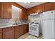 Functional kitchen featuring wooden cabinets, white appliances, and tile backsplash at 3021 Locust St, Denver, CO 80207