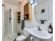 Bathroom with standing shower, vanity with bowl sink, storage cabinet, and round mirror at 11569 Grape St, Thornton, CO 80233
