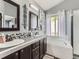Bathroom with dual sinks, dark wood cabinets, and soaking tub at 11569 Grape St, Thornton, CO 80233