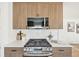 Close-up of the kitchen stove with wood cabinetry, white countertops, and stainless steel microwave at 2295 S Sherman St, Denver, CO 80210