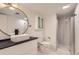 Stylish bathroom with modern vanity, round mirror, toilet, and glass-enclosed shower at 10295 E Evans Ave # 114, Aurora, CO 80247