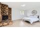 Cozy bedroom with stone fireplace, large clock and bright natural light from window at 10295 E Evans Ave # 114, Aurora, CO 80247