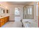 Open bathroom layout with a double sink vanity, bathtub, glass shower and arched window at 495 Bexley St, Highlands Ranch, CO 80126