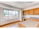 A kitchen has granite counter tops, light wood cabinets and island with a large window and hardwood floors at 495 Bexley St, Highlands Ranch, CO 80126
