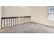 Bright loft featuring neutral carpet, a window, and wood railing overlooking the stairs at 2122 S Victor St # F, Aurora, CO 80014