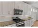 Close up of the kitchen featuring granite countertops, stainless steel appliances, tile backsplash, and white cabinets at 27307 E Costilla Pl, Aurora, CO 80016