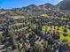 An aerial view captures the community's homes, bordering a golf course, set against a backdrop of rolling mountains at 15789 Sandtrap Way, Morrison, CO 80465