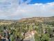 Expansive aerial view of a neighborhood nestled amongst mature trees, with rolling hills in the background at 15789 Sandtrap Way, Morrison, CO 80465