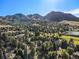 An aerial view shows a community surrounded by mountains, trees, and a golf course, with a serene lake nearby at 15789 Sandtrap Way, Morrison, CO 80465
