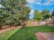 A flat, grassy backyard with wooden fence and mature trees in the background at 15789 Sandtrap Way, Morrison, CO 80465