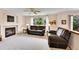 Bright living room featuring fireplace, ceiling fan, plush leather seating, and access to a dining area at 9717 Castle Ridge Cir, Highlands Ranch, CO 80129