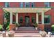 Charming red brick home showcasing a covered front porch with classic architectural details and potted flowers at 1275 N Franklin St, Denver, CO 80218