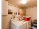 Functional laundry room featuring a washer, dryer, storage cabinets, and decorative wallpaper border at 11651 E Yale Way, Aurora, CO 80014