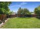 Green backyard with grass, a red brick house, and a wood fence on a sunny day at 1111 Kearney St, Denver, CO 80220
