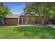 Well-maintained backyard with a brick house, grass, patio, a tree, and an air conditioning unit at 1111 Kearney St, Denver, CO 80220