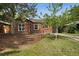 Quaint brick home featuring mature trees in the front yard, complemented by a dark roof and garage at 1111 Kearney St, Denver, CO 80220