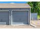 Individual garages featuring doors painted in stylish blue, each identified with unique unit numbers, and gabled roofs at 8335 Fairmount Dr # 10-208, Denver, CO 80247