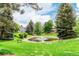 Relaxing view of the pond with a water feature, benches, and surrounded by mature trees and landscaping at 8335 Fairmount Dr # 10-208, Denver, CO 80247